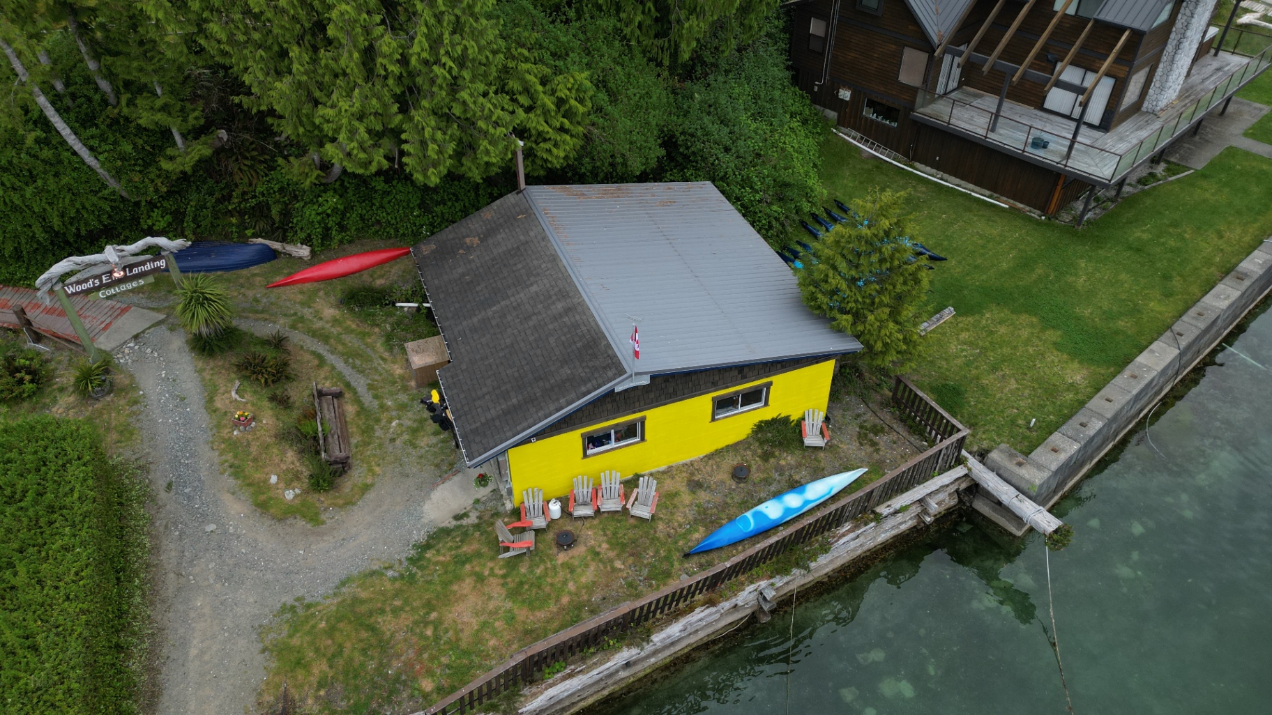 Yellow waterfront cabin at Wood's End Landing with kayaks and Adirondack chairs on Barkley Sound